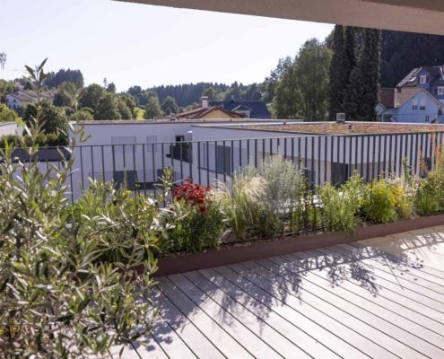 Sonnige Dachterrasse mit Holzbelag Sonnige Dachterrasse mit Holzbelag, bepflanzten Hochbeeten, Ziergräsern und blühenden Stauden als grüne Wohlfühloase.